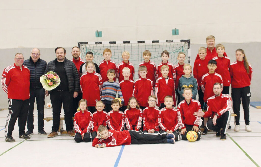 Auf dem Foto sind Oliver und Claus Drewes bei der Übergabe der Trainingsanzüge zu sehen.